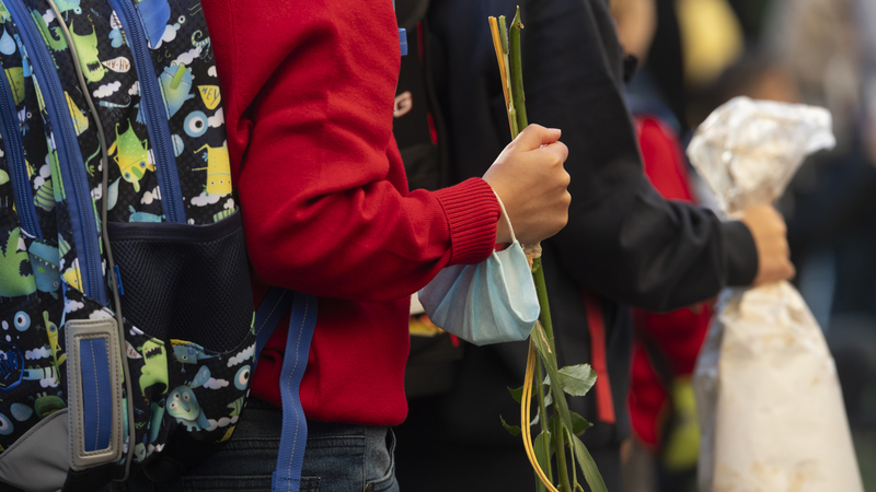 Žáci první třídy Základní školy Fr. Plamínkové v Praze stojí s květinami 1. září 2021 před budovou školy při zahájení nového školního roku.