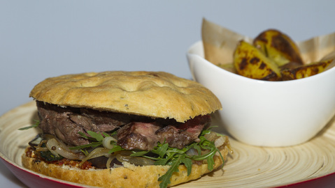 Focaccia s plátky hovězího masa, pečenou cibulí, cuketou a mesclun salátem