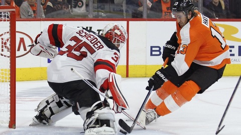 Kevin Hayes z Philadelphie se snaží zasunout kotouč za brankáře Coryho Schneidera.