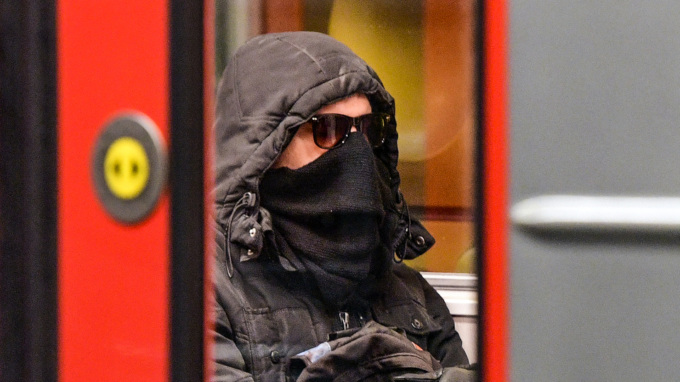 Muž se zakrytým obličejem v pražské MHD.