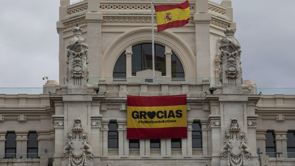 Nápis "Děkujeme" a "Zůstaňte doma" na španělské vlajce.