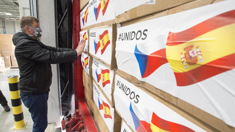 Ministr zahraničí Tomáš Petříček označuje nálepkami s českou a španělskou vlajkou krabice s humanitární pomocí České republiky, které 29. března 2020 odvážely kamiony z policejního skladu v Opočínku u Pardubic.