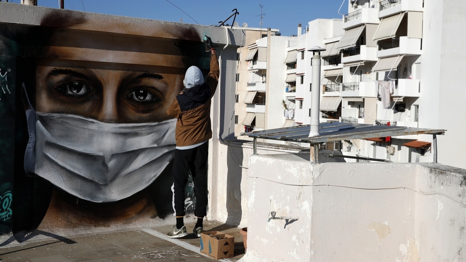 Umělec v Řecku nabádá k nošení roušek.