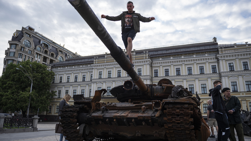 Muž se prochází po hlavni zničeného ruského tanku, který je vystaven na Michajlovském náměstí, 27. května 2022, Kyjev, Ukrajina.