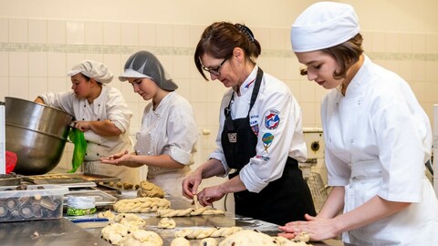 Učnice Střední školy řemesel a služeb v Děčíně a vedoucí učitelka odborného výcviku Pavlína Klopfštoková (druhá zprava) připravují vánočky, 2. prosince 2022, Děčín.